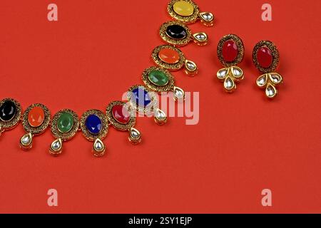 Gioielli tradizionali indiani su sfondo rosso con orecchini. Collana multicolore, gioielli femminili di lusso, gioielli tradizionali indiani, Bridal Gold We Foto Stock