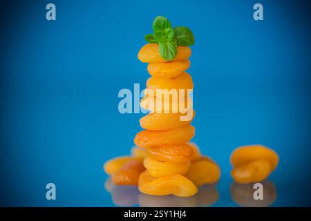 Composizione estetica con albicocche secche e menta fresca su sfondo blu. Foto Stock