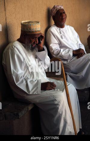 Uomo omanita che usa il telefono cellulare di Nizwa Market Oman Foto Stock