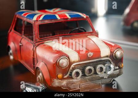Modello Mini Cooper britannico retrò con tetto Union Jack in mostra in un ambiente moderno che mette in mostra il fascino automobilistico d'epoca Foto Stock