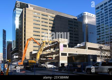 Ottawa, Canada - 26 febbraio 2024: Le gru lavorano per rimuovere neve e detriti da un garage multilivello in Slater Street, nel centro città. Una parte del garage è crollata la mattina presto, inviando mucchi di neve e cemento giù per tre livelli a terra e danneggiando diversi veicoli. La causa non è ancora stata determinata, ma potrebbe essere dovuta all'elevato livello di neve che non era ancora stato eliminato. La città ha ricevuto 70 centimetri di neve tra il 12 febbraio e il 16 febbraio. Foto Stock