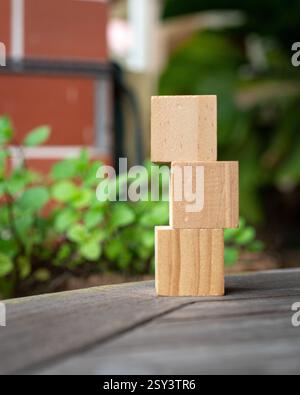 3 blocchi quadrati di legno vuoti impilati sul tavolo. Sfondo verde. Foto Stock