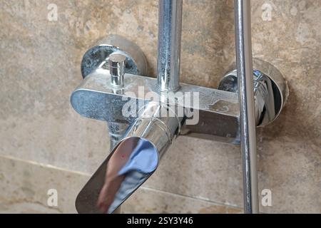 Rubinetto sporco con depositi di sale dall'acqua in bagno su moderne piastrelle scure in marmo. Pulizia e pulizia. Cura della casa e dell'ordine. Stile di vita. Foto Stock