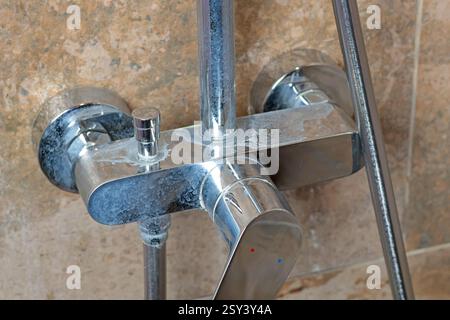 Rubinetto sporco con depositi di sale dall'acqua in bagno su moderne piastrelle scure in marmo. Pulizia e pulizia. Cura della casa e dell'ordine. Stile di vita. Foto Stock