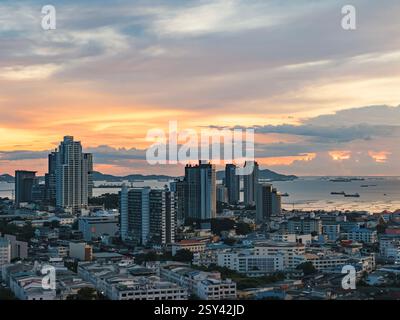 Splendido tramonto sullo skyline della città costiera con colori vivaci che si riflettono sull'acqua Foto Stock