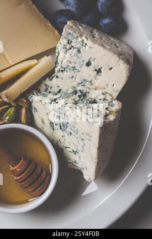 Formaggio erborinato (Roquefort) con miele, noci e frutti di bosco, primo piano. Foto Stock