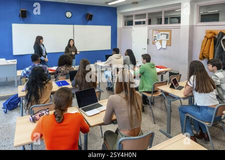 Gruppo multietnico di studenti delle scuole superiori che frequentano una lezione tenuta da due insegnanti in una classe del loro istituto universitario Foto Stock