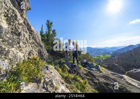 Due giovani donne si impegnano nell'arrampicata su roccia in una giornata di sole, circondate da bellezze naturali, con una vista mozzafiato della valle sottostante Foto Stock