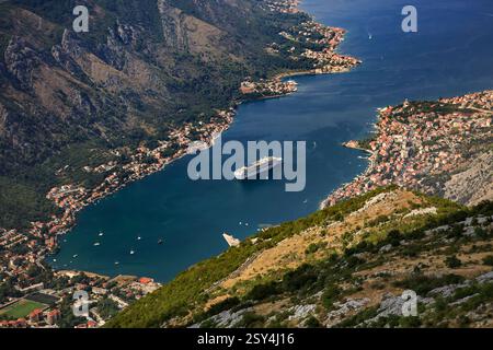 Una splendida vista aerea della baia di Cattaro in Montenegro, con una grande nave da crociera ancorata nelle acque blu profonde, circondata da montagne e. Foto Stock