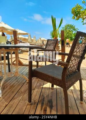 Caffè sulla spiaggia con tavoli e sedie in vimini sotto il baldacchino. Foto Stock