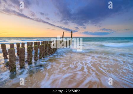 Onde che si infrangono sulla spiaggia in estate al tramonto con splendidi colori nel cielo - immagine di viaggio Foto Stock