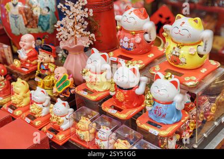 Vista ravvicinata del maneki-neko (gatto attraente). Fila di figure giapponesi in un negozio di souvenir al mercato centrale Foto Stock