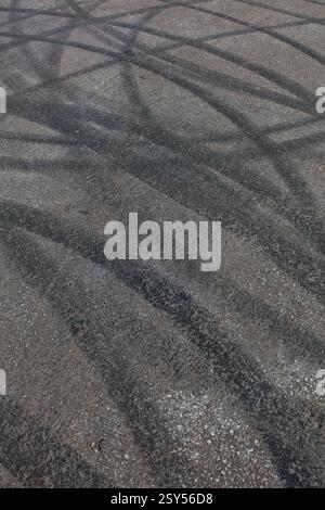 Primo piano dei cingoli di gomma bruciati sull'asfalto. Foto Stock