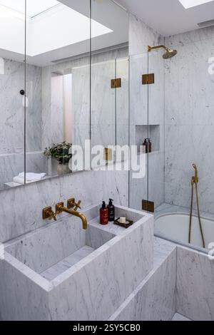 Armadietto a specchio sopra il lavandino in marmo con accessori da bagno in ottone in un ridesign contemporaneo della casa di West London. Foto Stock