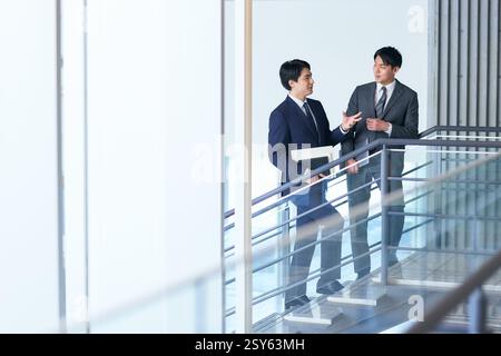 Due uomini d'affari in costume che parlano su Una scala Foto Stock