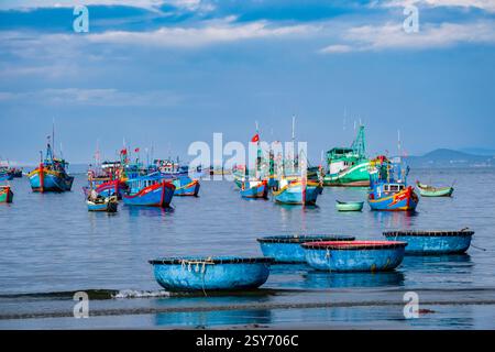 Tradizionali canottiere, in plastica, ancorate davanti alla spiaggia di Mui ne, MÅ i NÃ , molte barche da pesca in lontananza. MUI ne Binh Thuan Foto Stock