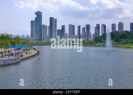 Sejong City, Corea del Sud - 26 maggio 2021: I visitatori si rilassano lungo la passeggiata sul lungomare del Sejong Lake Park, con una fontana nell'artificiale Foto Stock