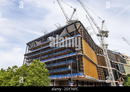 Edificio moderno in costruzione con gru a Londra, scenario di sviluppo urbano Foto Stock