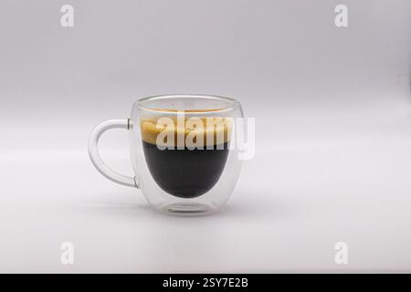Un espresso doppio, isolato in una tazza di caffè trasparente. Foto Stock