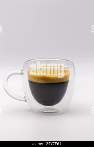 Un espresso doppio, isolato in una tazza di caffè trasparente. Foto Stock
