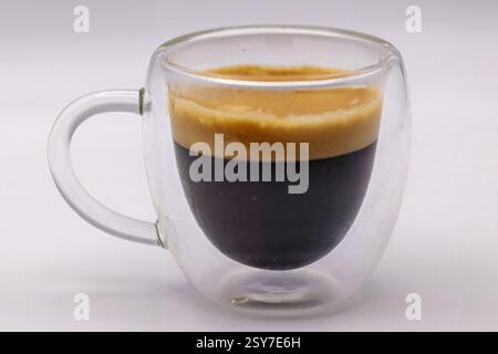 Un espresso doppio, isolato in una tazza di caffè trasparente. Foto Stock