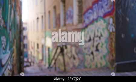 Strada urbana sfocata con vivaci graffiti che mostrano opere d'arte sfocate in un colorato vicolo del ghetto all'aperto, creando un'atmosfera dinamica e creativa. Foto Stock