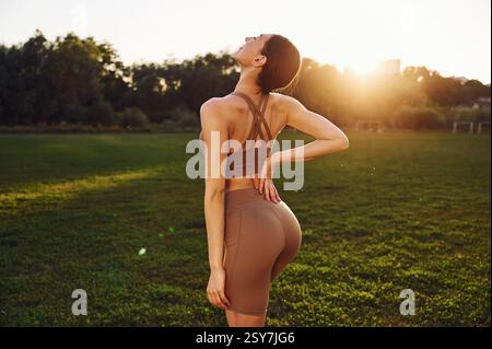 Contro la bella luce del sole. Una giovane donna in abiti da yoga è all'aperto sul campo. Foto Stock