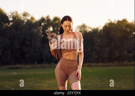 In piedi contro la foresta. Una giovane donna in abiti da yoga è all'aperto sul campo. Foto Stock