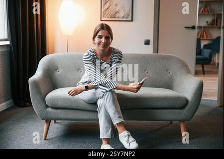 La giovane donna è seduta sul divano dell'appartamento. Foto Stock