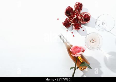 Composizione piatta con delizioso vino rosa e melograno su sfondo bianco. Spazio per il testo Foto Stock