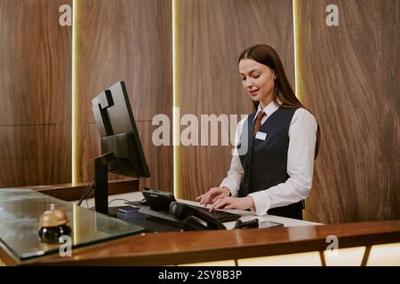 Ampia scelta di giovani receptionist caucasici che scrivono sulla tastiera mentre lavorano nella lobby dell'hotel Foto Stock