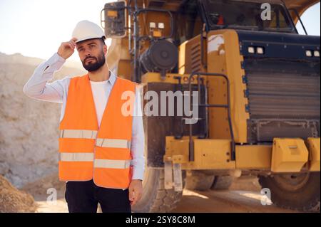 Un bell'uomo in uniforme lavora in cava di giorno. Con dumper da trasporto. Foto Stock