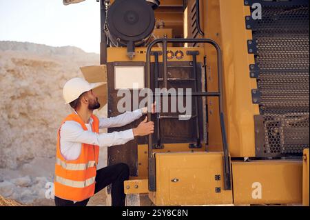 Un bell'uomo in uniforme lavora in cava di giorno. Con dumper da trasporto. Foto Stock
