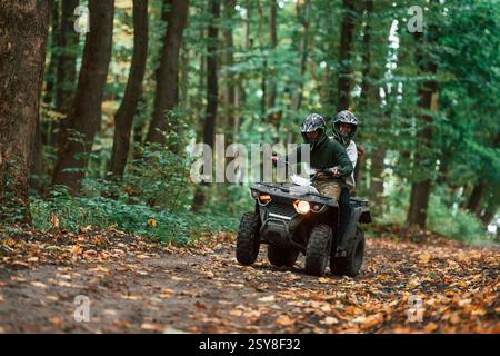 Guida sul sentiero. Giovane coppia in sella a un quad nella foresta. Foto Stock