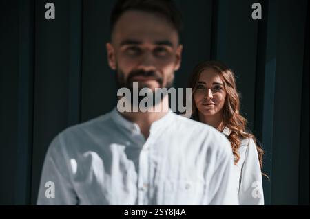 L'uomo è di fronte alla donna. Una bella giovane coppia sta in piedi insieme su uno sfondo verde scuro. Foto Stock