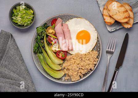 Fotografia gastronomica di colazione bilanciata, uovo fritto con quinoa, cavolo cinese, prosciutto, pomodori, cipolla primaverile, brindisi, fibre alimentari, cibo sano Foto Stock