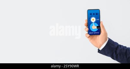 Mano dell'uomo con telefono cellulare che risponde all'indagine su sfondo chiaro con spazio per il testo Foto Stock