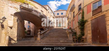 La storica Pujada de Sant Domenec a Girona, con gradini in pietra, un ponte ad arco e vecchi edifici con balconi, Spagna Foto Stock