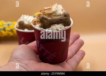 Una mano che tiene due tazze di caffè con un osso di cane sopra Foto Stock