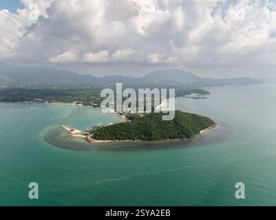 Una baia costiera circondata da acque turchesi e lussureggianti colline verdi con nuvole sparse nel cielo. Lipa noi. Koh Samui, Thailandia. Foto Stock