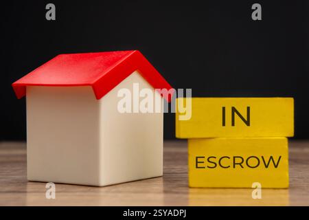 Una casa dei giocattoli con fino a due blocchi gialli impilati con le parole "IN DEPOSITO". Concetto di proprietà e proprietà immobiliari. Foto Stock