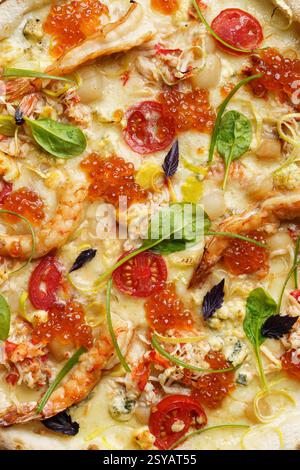 Vista ravvicinata di una pizza lussuosa adornata con succulenti gamberi, carne di granchio, capesante, caviale rosso e una varietà di formaggi tra cui mozzarella e b Foto Stock