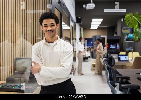 Un ambiente di ufficio moderno caratterizzato da un professionista sicuro in primo piano, con i colleghi impegnati in conversazioni in background, circondati Foto Stock