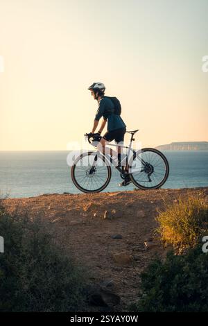 Un giovane che si diverte a fare un giro in bicicletta lungo i sentieri panoramici costieri di Zahara de los Atunes a Cadice durante un bellissimo tramonto. Foto Stock