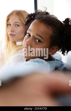 Due amici si rilassano su un divano, godendosi un momento tranquillo al coperto. Uno guarda direttamente nella fotocamera, mentre l'altro guarda attentamente. Illuminazione calda Foto Stock