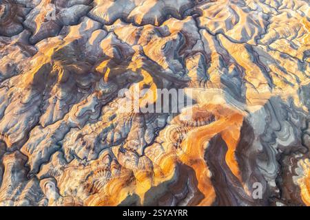 La vista aerea mostra le vibranti formazioni di bentonite nello Utah. I motivi vorticosi e i colori ricchi evidenziano la distinta geologia e l'arte naturale Foto Stock