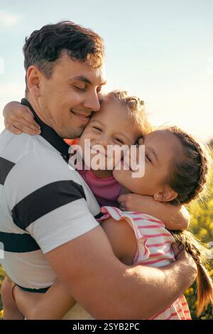 Un giovane padre e due figlie si divertono insieme all'aperto in estate. Buona genitorialità e infanzia Foto Stock