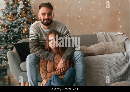 La donna è seduta. Una bella giovane coppia festeggia il nuovo anno a casa. Foto Stock