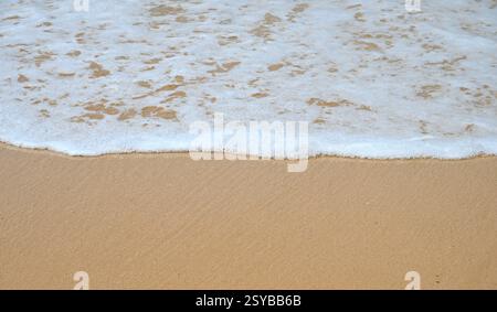 La splendida lacy Ocean WAVE sta facendo surf sulla spiaggia sabbiosa. Foto Stock