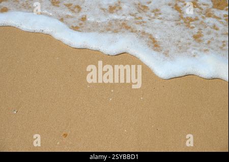 La splendida lacy Ocean WAVE sta facendo surf sulla spiaggia sabbiosa. Foto Stock